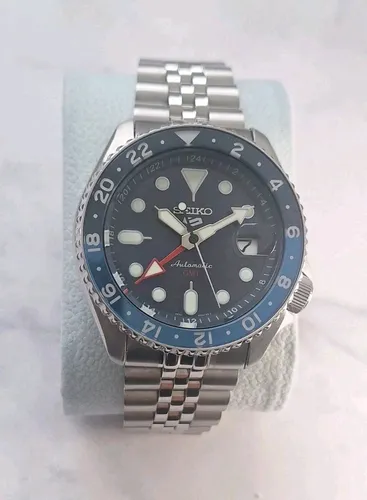 SEIKO 5 GMT AUTOMATIC Mod. BATMAN - Silber/Blau - Herrenuhr mit Automatikwerk, 10 bar wasserdicht und GMT-Funktion. Elegantes Design mit blauem Ziffernblatt und Sicherheitsfaltschließe.