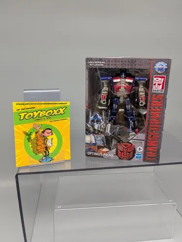 Transformers Universal Studios Deluxe Class Optimus Prime Figur - Actionfiguren für Kinder mit 2-in-1-Funktion: Die Optimus Prime Figur konvertiert in 12 Schritten von Roboter in Fahrzeugmodus und zurück, inklusive Blaster und Energon-Axt.